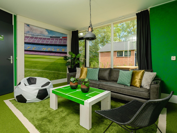 Het interieur van de Voetbal-lodge op Vakantiepark Molke, met een salontafel in de vorm van een voetbalveld en een zitzak als voetbal.