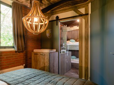Het sfeervolle, houten interieur van de boomhut op Vakantiepark Molke, met een doorkijkje naar de knusse bedstee voor de kinderen.