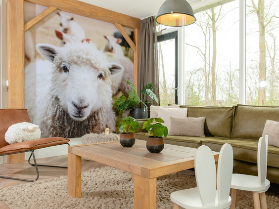De gezellige woonkamer van een Boerderij-lodge op Vakantiepark Molke, met een grote fotowand van een schaap.