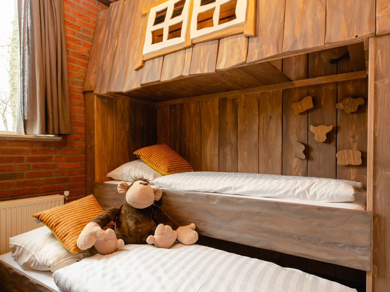 Een knus houten stapelbed in een boomhut op Vakantiepark Molke, met een aap-knuffel op het onderste bed.