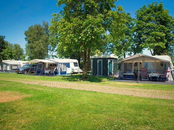 Een ruime, groene kampeerplaats met een caravan en voortent op de camping van Vakantiepark Molke in Overijssel.