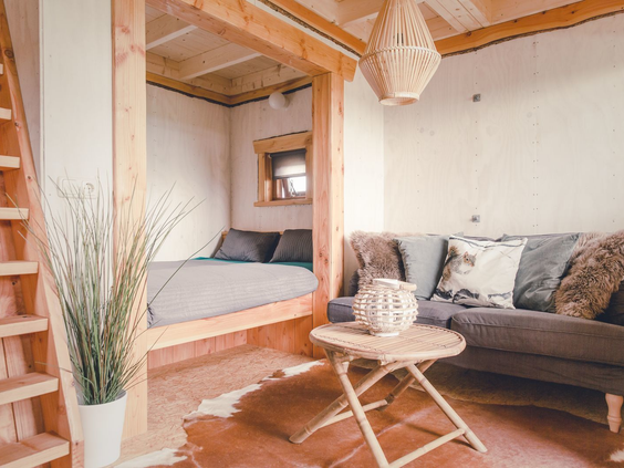 De gezellige woonkamer en bedstee in een boomhut op Vakantiepark Molke, ingericht met natuurlijke materialen en uitzicht naar buiten.