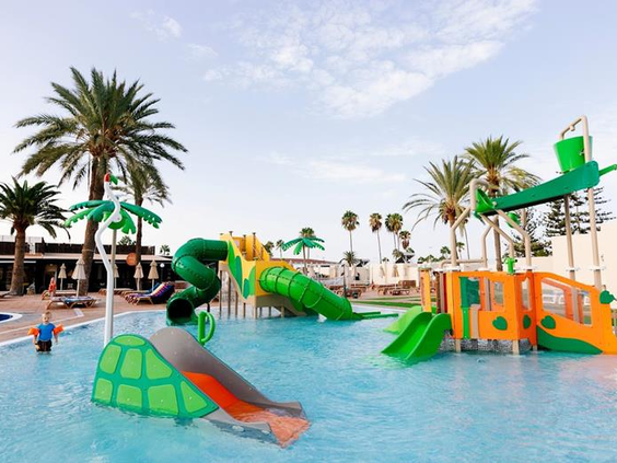 De kleurrijke waterspeeltuin van Parque Cristobal op Gran Canaria met diverse glijbanen en waterspuiters voor kinderen.
