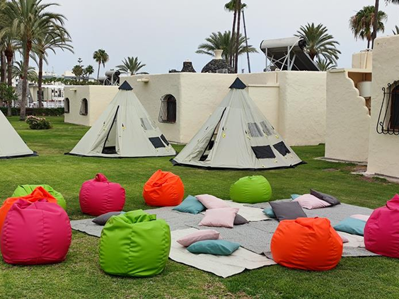 De gezellige chill-out zone voor kinderen bij Parque Cristobal met tipi tenten en vrolijk gekleurde zitzakken op het gras.