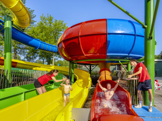 Kinderen glijden door de kleurrijke bochten van de grote waterglijbaan