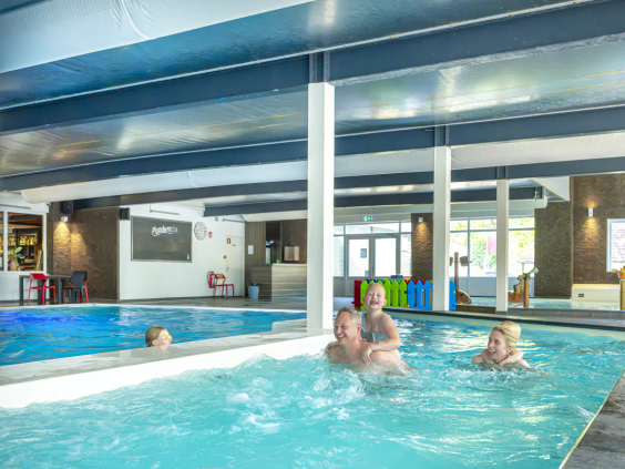 Gezin zwemt samen in het overdekte zwembad van de camping