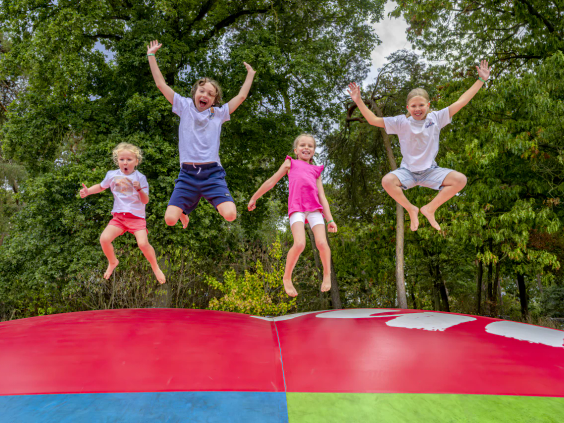 Vier kinderen springen tegelijkertijd hoog in de lucht op de grote airtrampoline