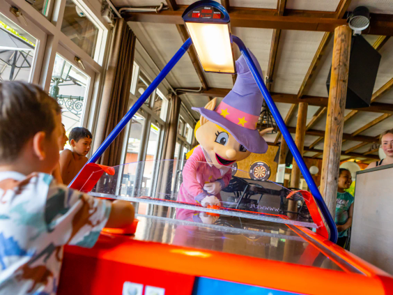 Kind speelt een potje airhockey in de overdekte speelhal van de camping