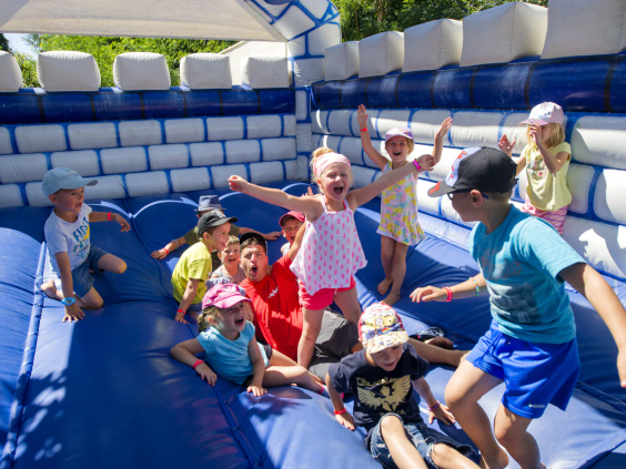 Kinderen springen en spelen op een groot wit-blauw opblaasbaar springkussen