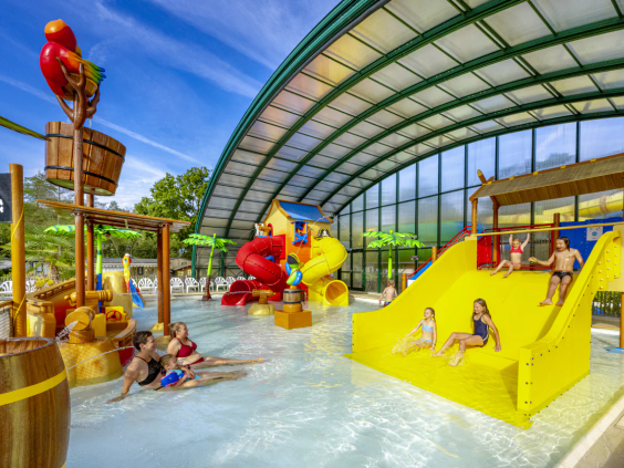 Kleurrijke binnenspeeltuin met water en een brede gele glijbaan voor kinderen