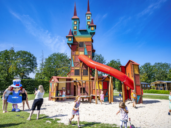De hoge magische Carabouille speeltoren met rode glijbaan op de camping