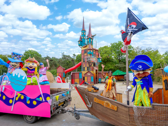 Een kleurrijke praalwagen in de vorm van een piratenschip met mascottes op de camping