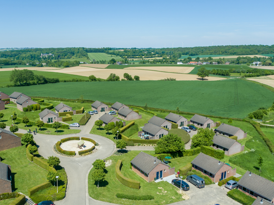 Luchtfoto van de vakantiehuisjes van Vakantiepark Reevallis, gelegen in het glooiende heuvellandschap van Zuid-Limburg.