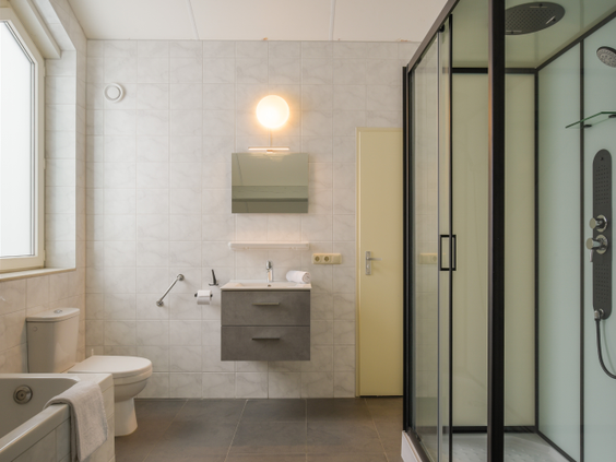 Moderne badkamer met een ruime inloopdouche, ligbad en wastafel in een vakantiebungalow.