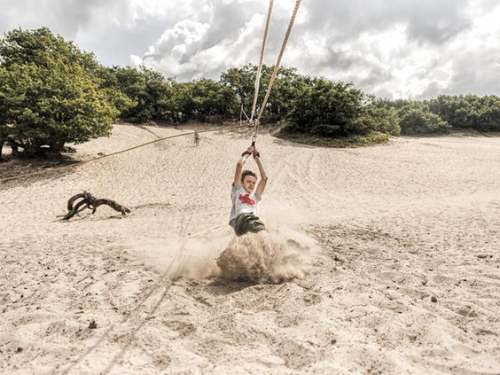 Een kind speelt op een kabelbaan in de zandduinen van natuurgebied Herperduin, direct naast Vakantiepark Schaijk.