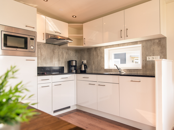 De moderne, witte keuken in een vakantiehuisje op Vakantiepark Slagharen, voorzien van een magnetron en kookplaat.