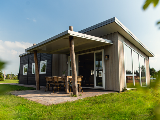 De buitenkant van een moderne Rancheda Lodge accommodatie op Vakantiepark Slagharen met een overdekt terras.