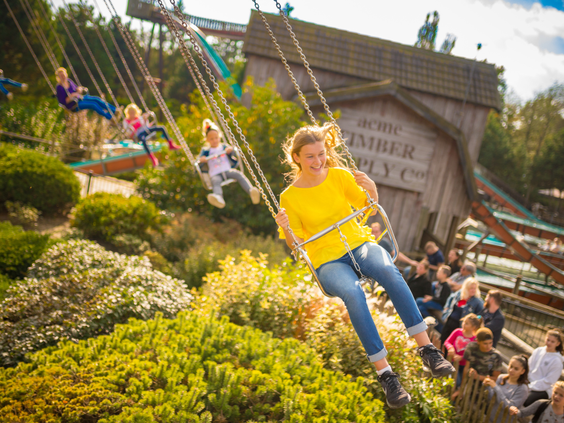 Bezoekers, waaronder een meisje in een gele trui, hebben plezier in de hoge zweefmolen in Attractiepark Slagharen.