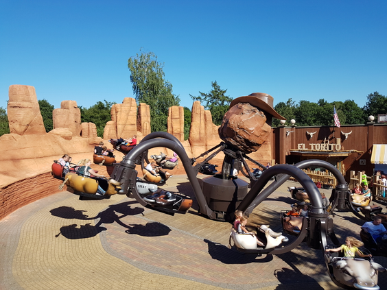 Bezoekers in de draaiende attractie El Torito, ook wel de 'octopus' genoemd, in een Western-thema bij Attractiepark Slagharen.