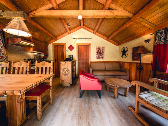 De gezellige en rustieke houten inrichting van een Cowboy Cottage op Vakantiepark Slagharen, met stapelbedden en een rode stoel.