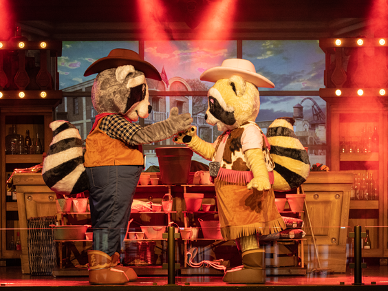 De wasbeer mascottes Randy en Rosie in een show op het podium in een Western saloon setting in Attractiepark Slagharen.