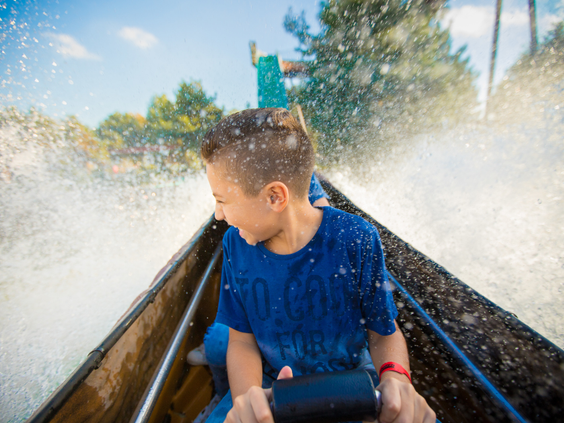 Een jongen in een boomstam in de wildwaterbaan Ripsaw Falls in Slagharen wordt nat van de opspattende golven.
