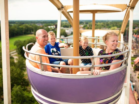 Een familie geniet van het uitzicht over het attractiepark vanuit een bakje in het reuzenrad van Slagharen.