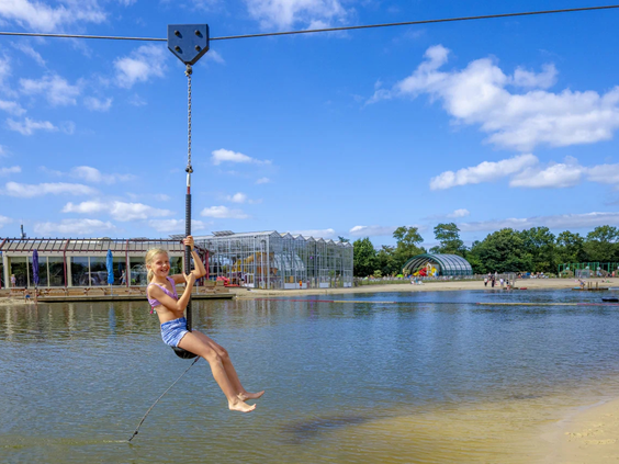 Kind zoeft aan de kabelbaan over het water van het recreatiemeer