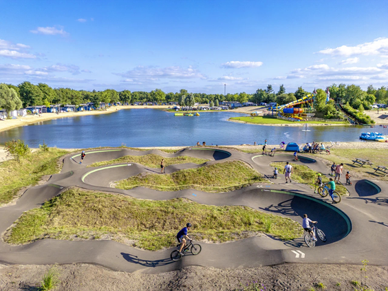 Bovenaanzicht van de pumptrack baan en het recreatiestrand bij het meer