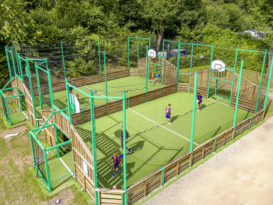 Kinderen spelen voetbal in de omheinde sportkooi op het park
