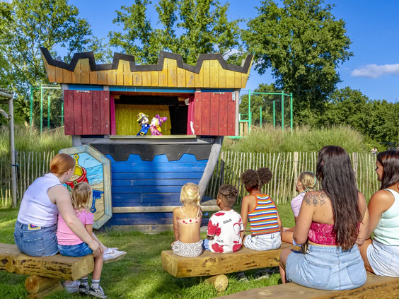 Kinderen kijken naar een poppenkastvoorstelling in de buitenlucht