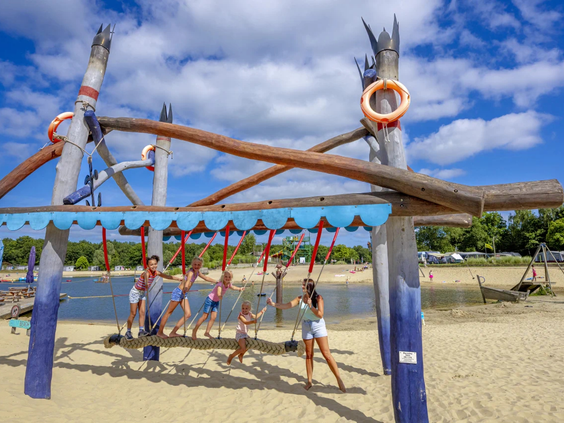 Groot houten speeltoestel op het zandstrand bij het recreatiemeer