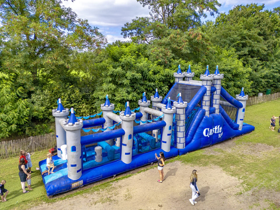 Groot blauw opblaasbaar springkussen op het grasveld van de camping