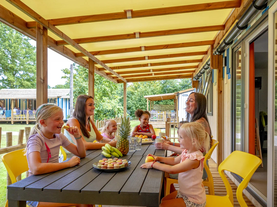 Familie geniet van een gezellig diner op de veranda van hun chalet