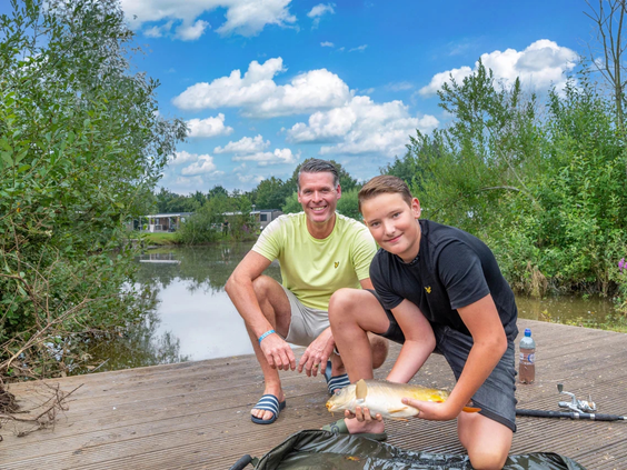 Twee jongens zijn aan het vissen aan de oever van het recreatiemeer