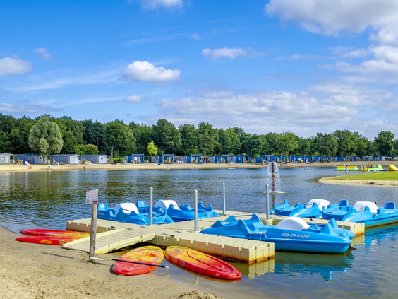 Waterfietsen en kano's liggen klaar voor gebruik op het zandstrand