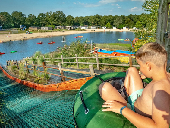 Jongen glijdt met hoge snelheid van de waterglijbaan op het park
