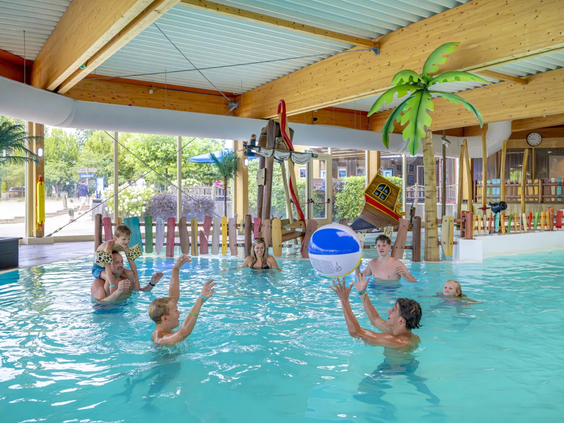 Kinderen spelen in het verwarmde binnenzwembad met tropische decoratie