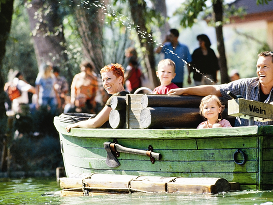 Een familie geniet van een rustige boottocht in een groene boot-attractie in Erlebnispark Tripsdrill.