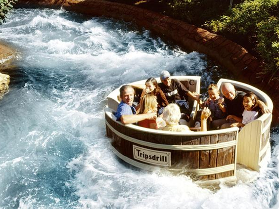 Een familie heeft plezier in een rond, houten wasvat in de kolkende wildwaterbaan-attractie van Erlebnispark Tripsdrill.