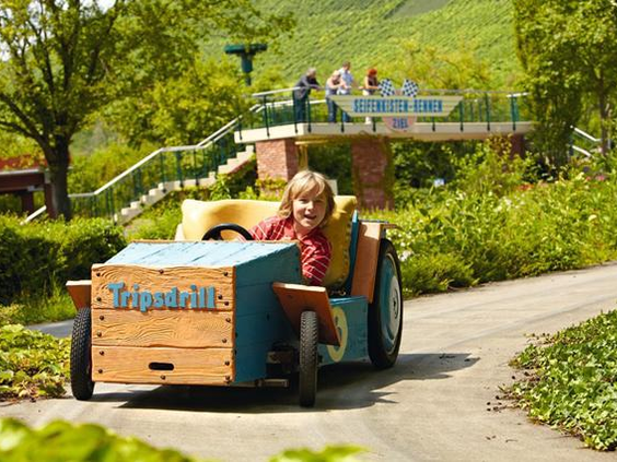 Een jongetje rijdt lachend in zijn eigen houten zeepkist tijdens de zeepkistenrace-attractie in Erlebnispark Tripsdrill.