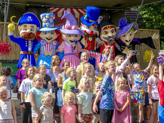 Een grote groep kinderen poseert met de mascottes van het animatieteam
