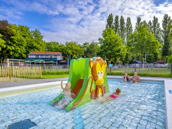 Een klein peuterbad met een vrolijke groene kikkerglijbaan