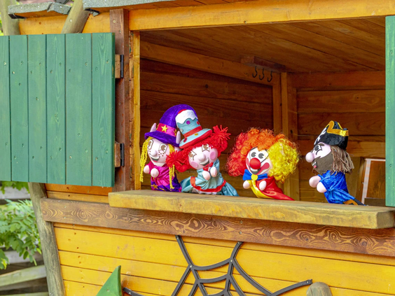 Mascottes geven een poppenkastvoorstelling vanuit een houten huisje