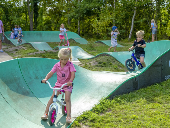 Een kind op een fiets op de golvende pumptrack baan van de camping