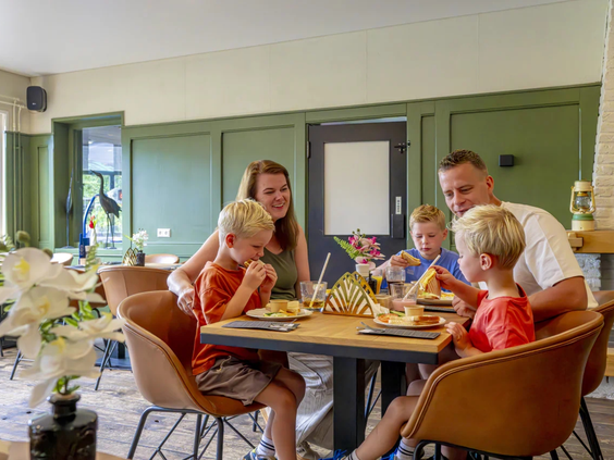 Een gezin geniet van een maaltijd in het sfeervolle restaurant op het park
