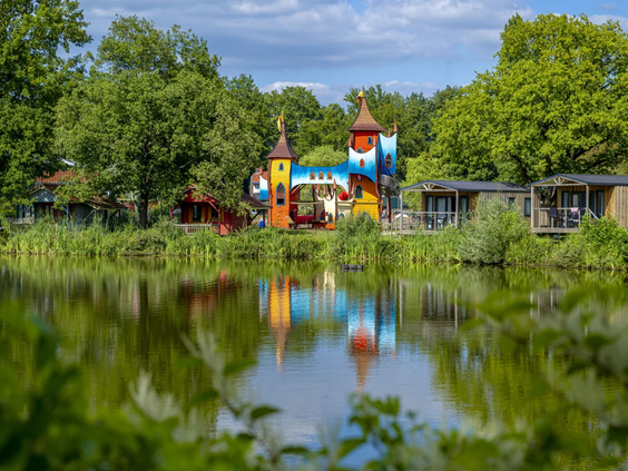 Houten speeltoestel gelegen in het gras bij de vijver