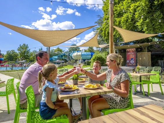 Gezin geniet van een lunch op het zonnige terras van het restaurant