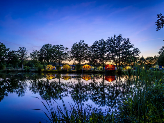 De vijver op de camping tijdens de schemering met verlichting