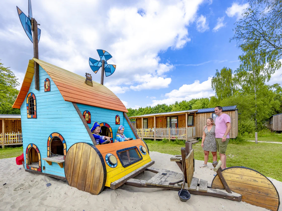 Een uniek blauw houten speelhuisje op wielen in de speeltuin